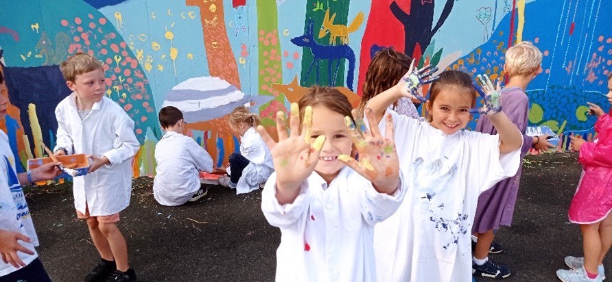Les CE1 ajoutent leur touche à la fresque de l’école.